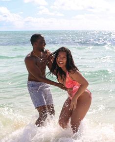 a man and woman are playing in the water at the beach while one holds his arm around the other's waist