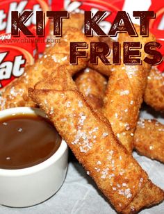 a pile of fried chicken sticks next to a cup of dipping sauce and two packets of kitkat