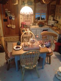 a doll house kitchen and dining table with chairs, plates and bowls on the table