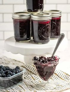 blueberries and jam in jars on a cake stand