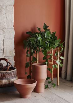 three planters in front of a brick wall with a basket on the floor next to them