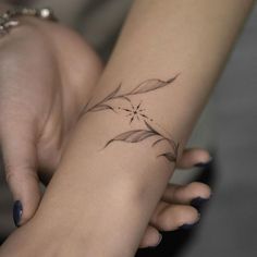 a woman's hand with a small tattoo on her left wrist and the other arm