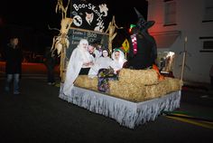 some people are dressed up in costumes and sitting on a hay bale float at night