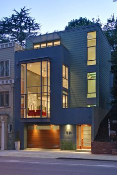 a modern house with lots of windows on the front and side of it at night