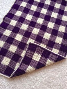 a purple and white checkered blanket laying on the floor