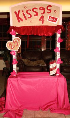 a pink table with a sign that says kiss's sale on it and two hearts at the top