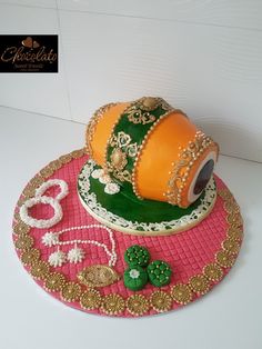 a cake that is sitting on top of a pink table cloth with gold and green decorations