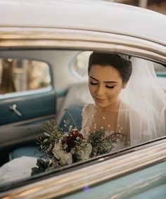 a woman in a wedding dress is looking out the window of a car with her bouquet