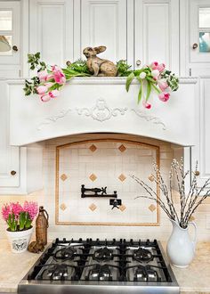 a stove top oven sitting inside of a kitchen next to a vase filled with flowers