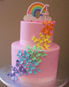 there is a pink cake with rainbows and stars on the top, along with other decorations