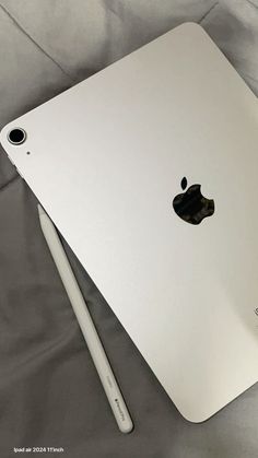 an apple laptop computer sitting on top of a white sheet with a pen next to it