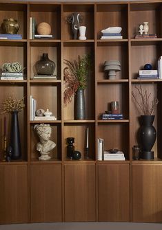 a wooden bookcase with vases and books on top of it in a living room