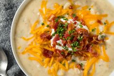 a white bowl filled with soup topped with bacon and cheese