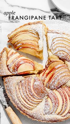 an apple tart is cut into slices and served on a platter with serving utensils