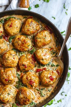 a pan filled with meatballs covered in sauce and garnished with parsley