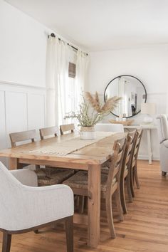 a dining room table with chairs and a mirror in the back ground, next to a couch