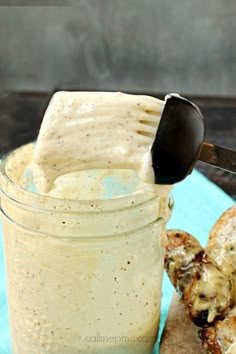 a glass jar filled with dressing next to bread