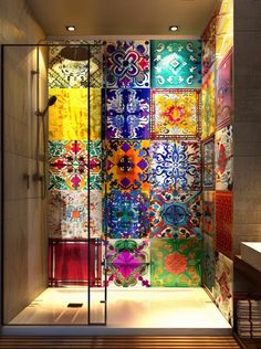 a bathroom with colorful tiles on the wall and shower stall in front of it's glass door