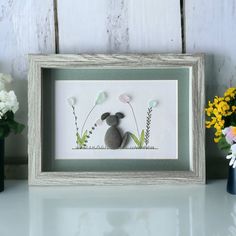 a white frame holding a stuffed animal and flowers