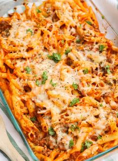 a glass casserole dish filled with pasta and meat, topped with parmesan cheese