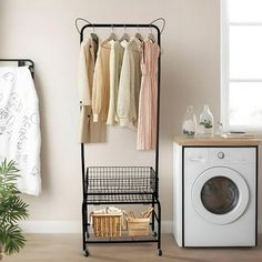 a laundry room with clothes hanging on the rack and a washing machine next to it