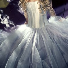 a woman in a white dress is posing for the camera with her long curly hair