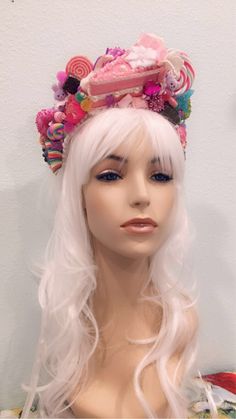 a wig with long white hair wearing a pink hat and candy land on it's head