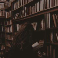 a woman standing in front of a bookshelf filled with lots of bookcases