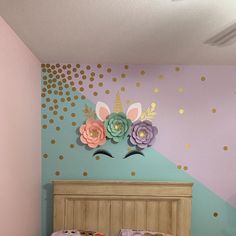 a child's bedroom decorated in pastel colors with gold polka dots and paper flowers