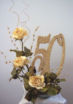 a 50th birthday cake decorated with flowers and gold glitter number 50 on a marble block