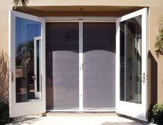 an open door to a building with glass doors on both sides and palm trees in the background