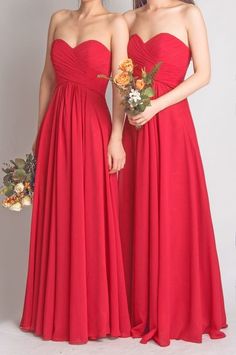 two bridesmaids in red dresses standing next to each other and holding bouquets