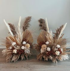 two vases filled with dried flowers and feathers