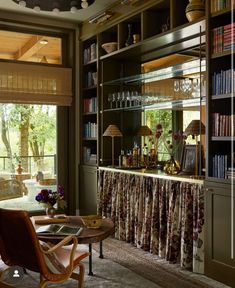 a living room filled with furniture and bookshelves next to a large glass door