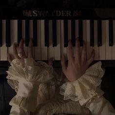 a person with their hands on the keys of an old fashioned piano in a dark room