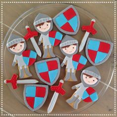 decorated cookies in the shape of knights with swords and shields on a glass platter