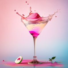 a pink liquid splashing into a martini glass with a slice of watermelon