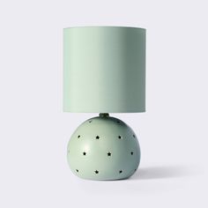 a green lamp sitting on top of a table next to a white light bulb with stars on it