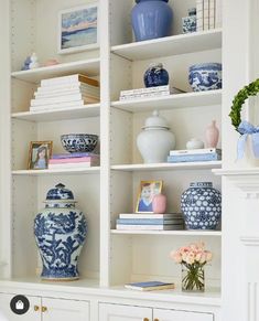 a white bookcase with blue and white vases on it