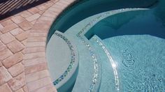 an outdoor swimming pool with mosaic tile and stone pavers