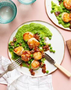 two white plates topped with shrimp and pea salad next to glasses of green liquid on a pink surface