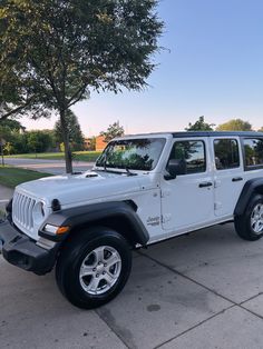 a white jeep is parked on the sidewalk