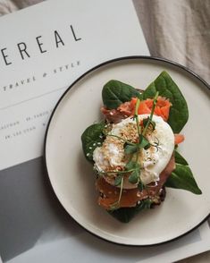 a white plate topped with an egg and veggie salad next to a menu