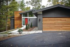 a modern house with wood siding and red door