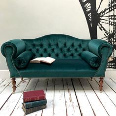 a green couch sitting on top of a wooden floor next to two bookends