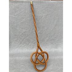 a wooden object is hanging from a rope on a gray cloth background with gold colored handles