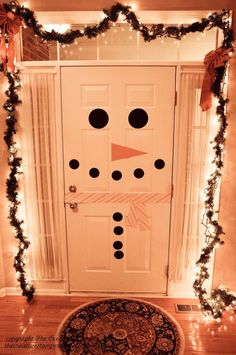 a snowman door decorated with christmas lights and garland on the front entrance to a house