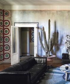 a living room filled with furniture and a tall cactus in the middle of the room