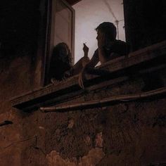 two people sitting on a window sill in the dark