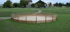 a wooden fence around a circular structure in the middle of a field